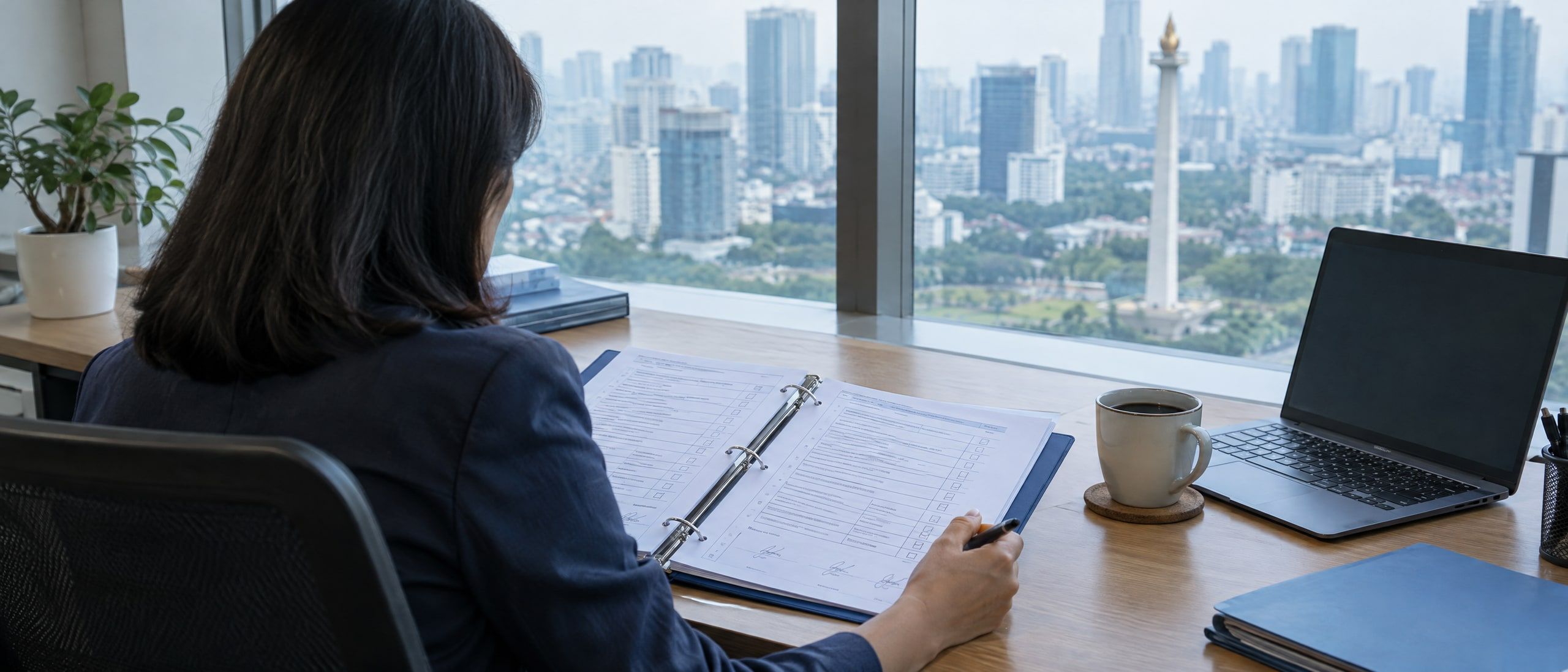 A finance controller reviewing a binder of signed control checklists beside a laptop